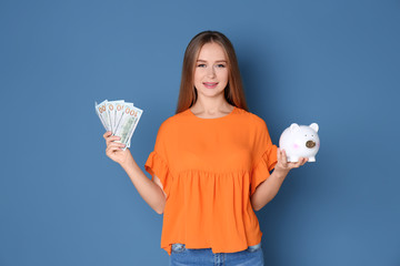 Young woman holding piggy bank and money on color background