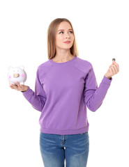 Obraz premium Young woman holding piggy bank and coin on white background