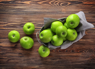 Basket with fresh green apples on wooden background