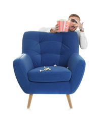 Naklejka premium Scared man with 3d glasses and popcorn hiding behind armchair during cinema show on white background