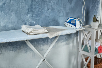 Stack of clean white napkins on ironing board indoors