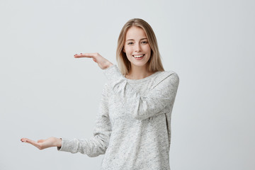 Good-looking beautiful blonde with dyed hair woman in casual clothes shows with hands length of...