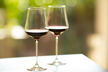 Closeup of two red wine glasses with a colorful, sunny atmosphere. Summer ambience, low depth of field