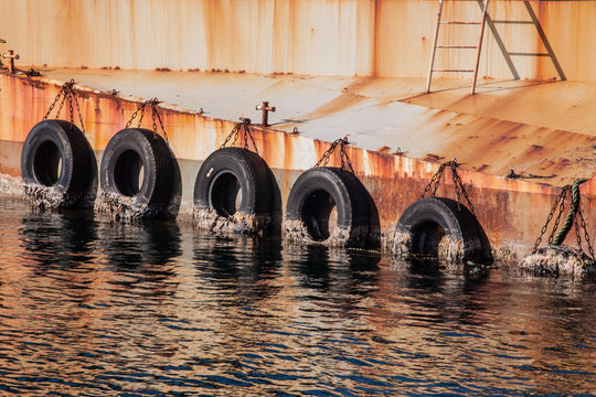 Abstract, modern harbour impression &ndash; reflective scenery of tires on a rusty wall during sunset in Reykjavic, Iceland