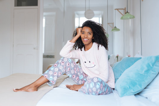 Happy beautiful young black woman relaxed sitting in the bed .