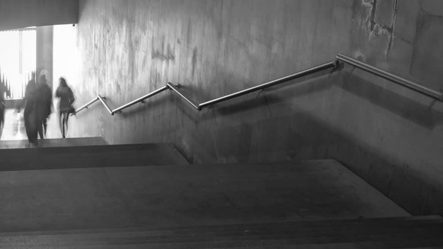 Time Lapse of black and white pictures of walking people on the stairs. Camera moving.