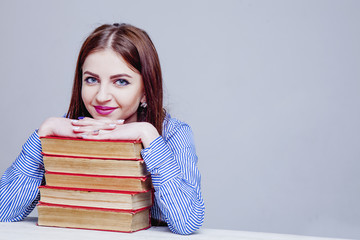 Beautiful young woman on books as a symbol of desire to develop, learning and gaining knowledge