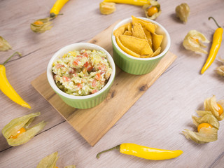 Guacamole from avocado delicious Mexican food. Guacamole with tortilla chips dish. Organic food composition on the wooden table. Healthy vegetarian food on the white wooden background. Healthy food.