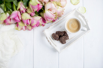Fototapeta na wymiar bouquet of roses on a white background and a cup of coffee with chocolate