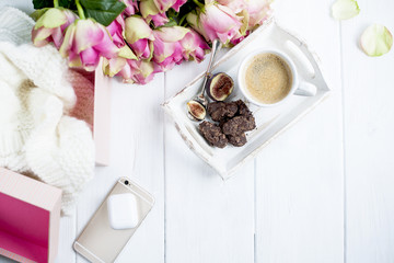 a bouquet of roses on a white background and a cup of coffee with chocolate and a phone with headphones