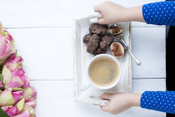 a bouquet of roses on a white background and a cup of coffee with chocolate in the hands of a girl