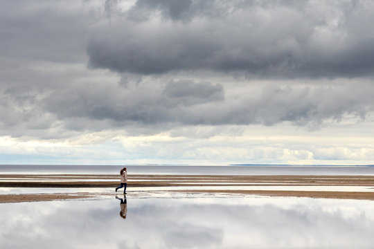 Woman on the beach run, cloudy weather