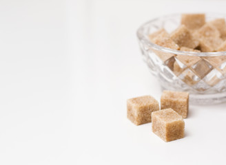 Cane sugar cubes in the sugar bowl on white background