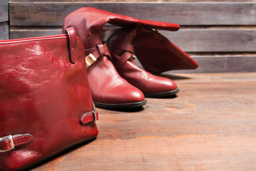 Red bag and high boots on wooden background