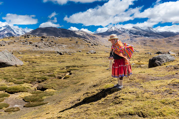 Peruvian indigenous old woman standing weaving traditional cloths, Peru.