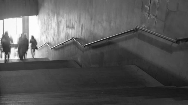Time Lapse of black and white pictures of walking people on the stairs. Camera zoom out
