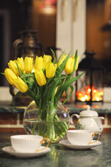 A bouquet of yellow tulips in a vase in the interior of a retro 