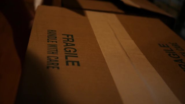 Close up of fragile cardboard box being picked up by postal worker