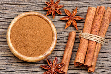 Bowl with cinnamon powder and sticks with anise star on table