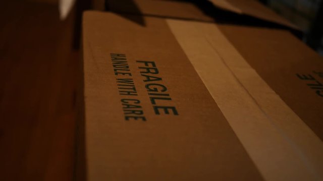 Postal worker sets down a fragile cardboard box on wooden floor