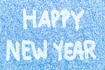 HAPPY NEW YEAR text message hand written on blue ice frosted window background in white snow. Photo of real snowflakes texture frozen outside with handwriting happy new year painted on top. 2018.