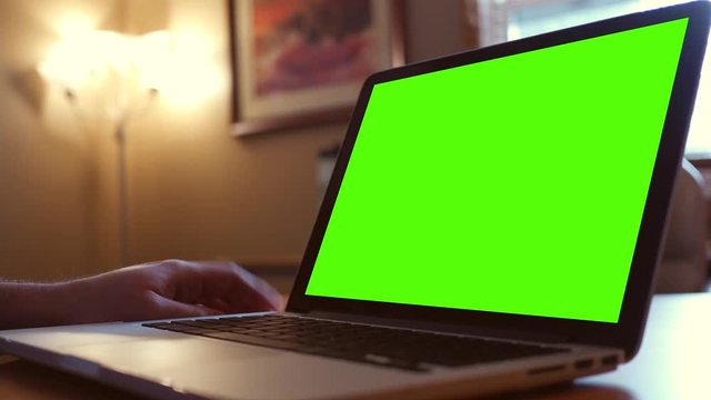 Green Screen laptop in office room with impatient hand tapping desk