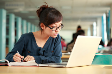 one female asian college students study at laptop in the library