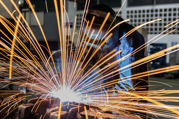 Worker is welding assembly part in car factory
