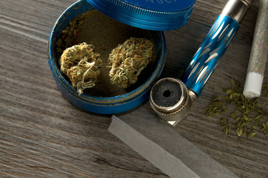 Cannabis, Grinder, Pipe, Joint and Paper on Table