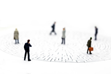 Miniature people: Businessman teams standing on center of maze