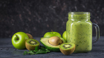 Smoothies from avocados, bananas, kiwi and herbs on a black table. Diet vegetarian food.