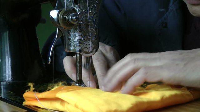 An old man is operating a sewing machine