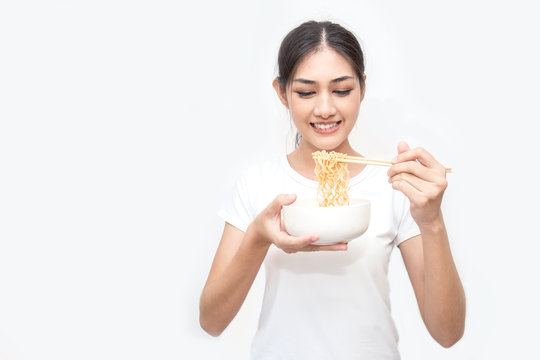 Young beautiful asian woman eating yummy hot and spicy instant noodle using chopsticks isolated on white background. Asian girl servile end of the month with cheap food.