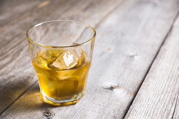 Glass with whiskey on the rustic wooden background. Selective focus. Shallow depth of field.