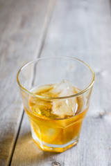 Glass with whiskey on the rustic wooden background. Selective focus. Shallow depth of field.