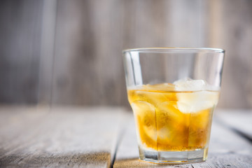 Glass with whiskey on the rustic wooden background. Selective focus. Shallow depth of field.