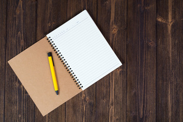 Notebook and empty white paper with pen on wood table top view with copy space