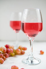 Pink wine and a grape on the white background