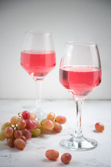 Pink wine and a grape on the white background