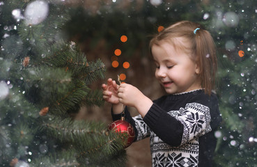 A little child by the New Year tree. Children decorate the Chris