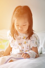 asian kid sick and relax on bed with sunrise. She is uncomfortable and is being treated the best.