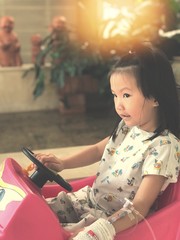 asian kid sick and relax on car toy with sunrise. She is uncomfortable and is being treated the best.