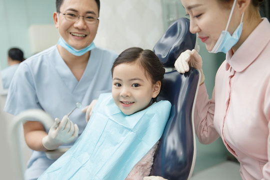 The dentist and the dentist's assistant are examining the tooth for the little girl