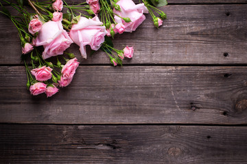 Border from tender pink roses flowers  on  aged wooden background.
