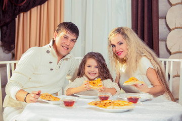 Family eating dinner at a dining table, Round table, pizza, orange, house made of wood