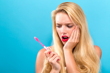 Young woman with toothache while brushing her teeth