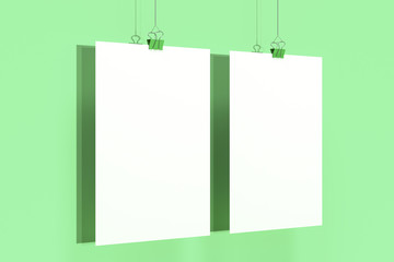 Two blank white posters with binder clip mockup on green background