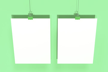 Two blank white posters with binder clip mockup on green background