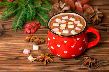 Obraz na płótnie Canvas hot chocolate with marshmallow candies on wooden background decorated Christmas tree branch, cones and anis, greeting card