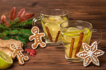 Christmas cup of tea with ginger, lime and cinnamon on wooden background, festive background